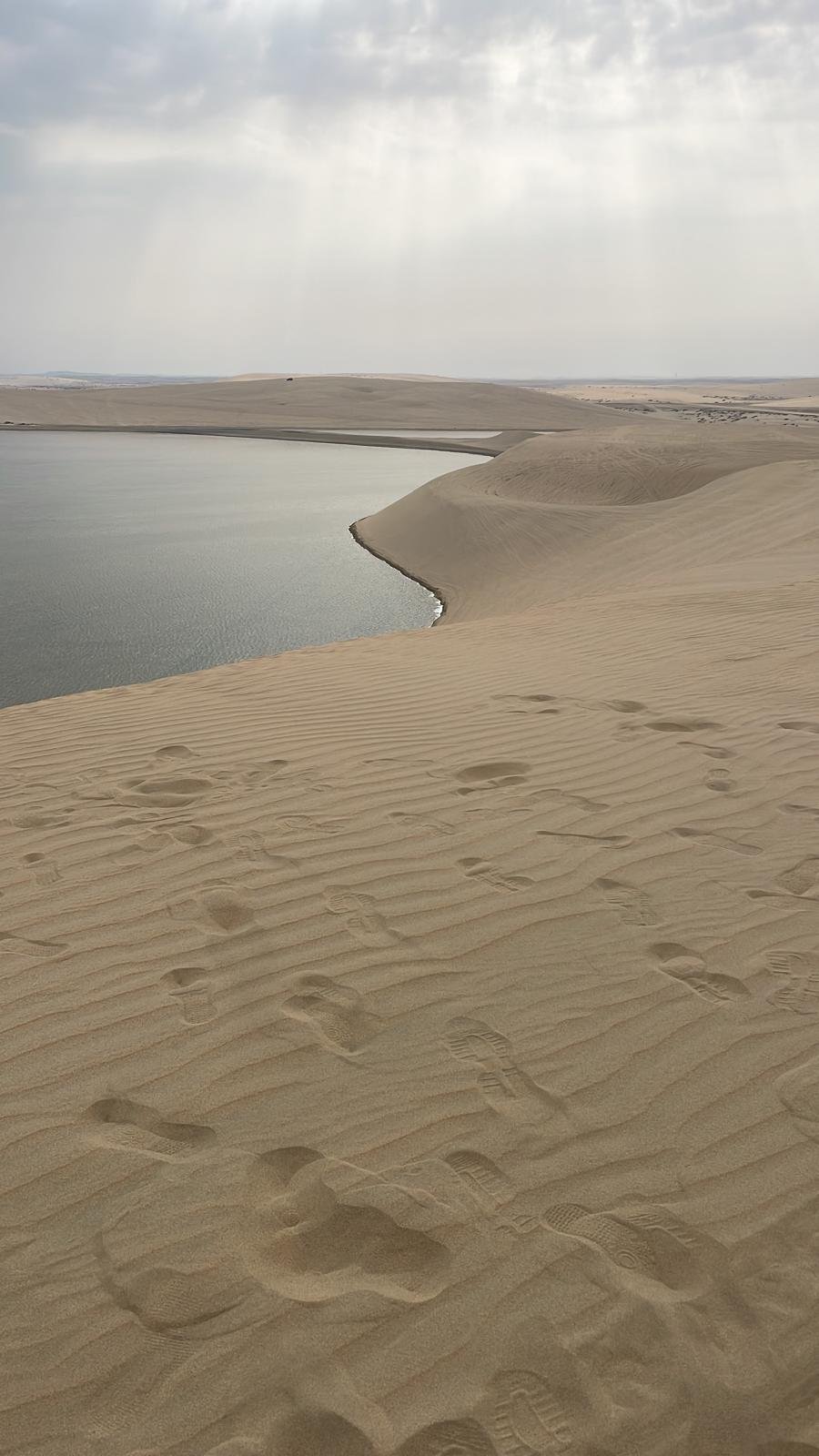 Footprints across a dune ridge above the Inland Sea at Khor Al Adaid